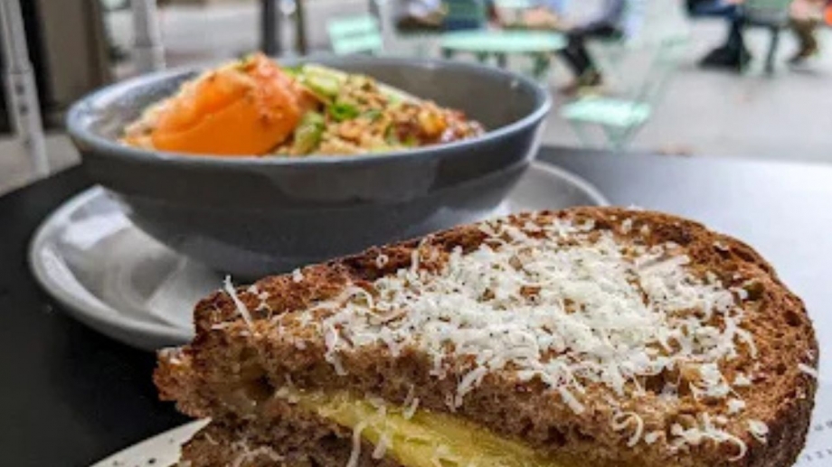 Fresh cherry Danish pastry dusted with powdered sugar, paired with a creamy latte on a saucer at Hill Bros Cafe.